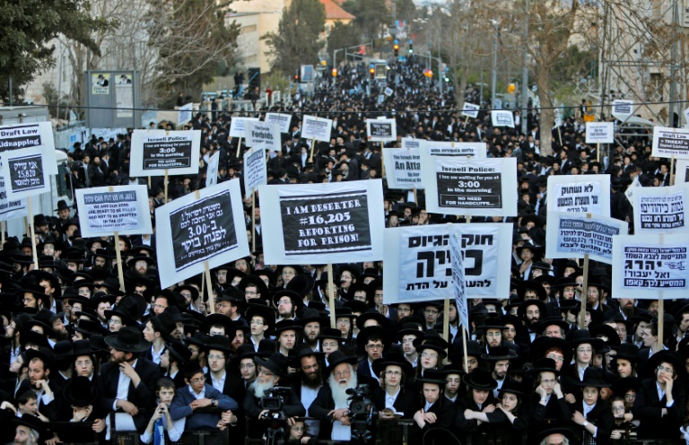 Judeus ultraortodoxos seguram cartazes durante protesto contra o serviço militar obrigatório, em Jerusalém, em 28 de março de 2017 - AFP