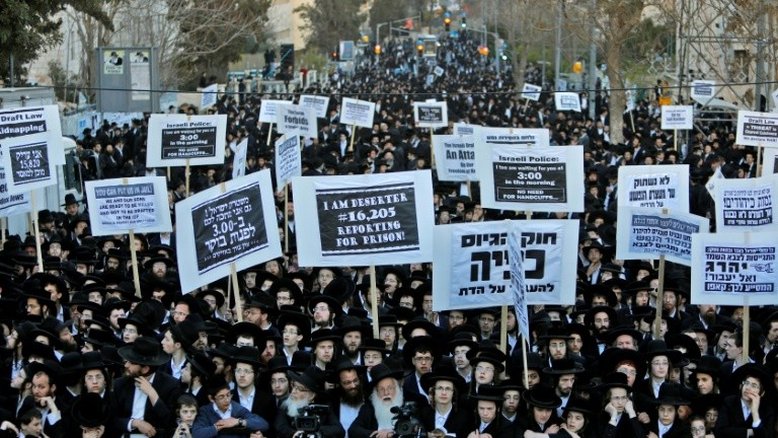 Judeus ultraortodoxos seguram cartazes durante protesto contra o serviço militar obrigatório, em Jerusalém, em 28 de março de 2017 - AFP