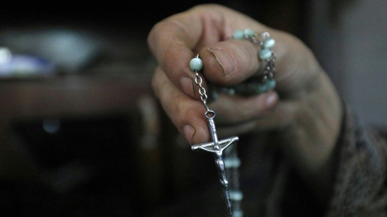 Com um terço na mão e dois papagaios na outra, uma cristã foge de Raqa