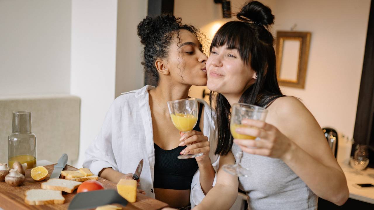 mulher segurando taça e beijando bochecha de outra mulher, melhorar o sexo