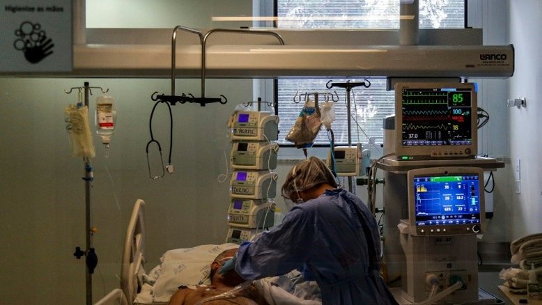 Profissional de saúde supervisiona um paciente com COVID-19 na unidade de cuidados intensivos do hospital Emílio Ribas, em São Paulo, 20 de abril de 2020 - AFP