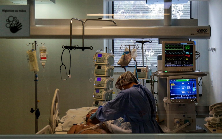 Profissional de saúde supervisiona um paciente com COVID-19 na unidade de cuidados intensivos do hospital Emílio Ribas, em São Paulo, 20 de abril de 2020 - AFP