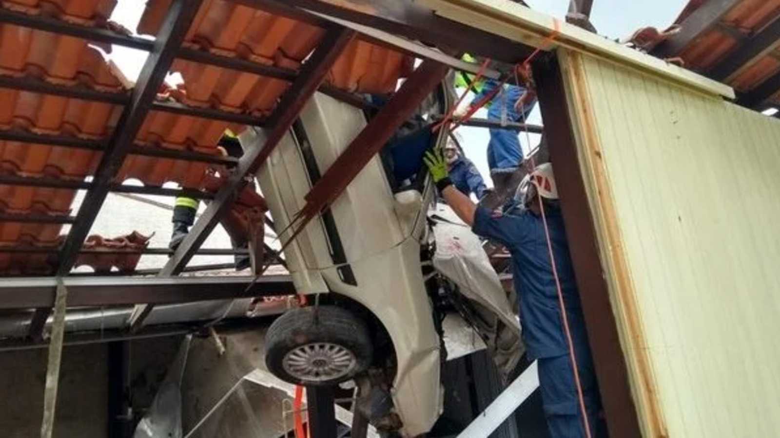 SC: Motorista perde controle e carro fica pendurado em telhado de confecção