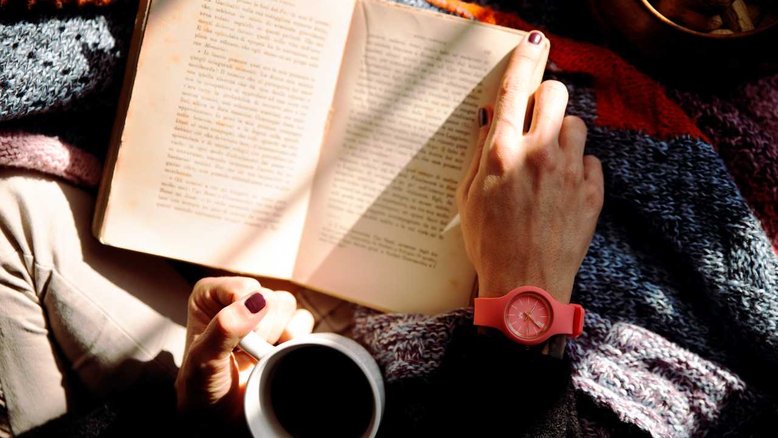 mulher segurando livro e xícara, bem-estar