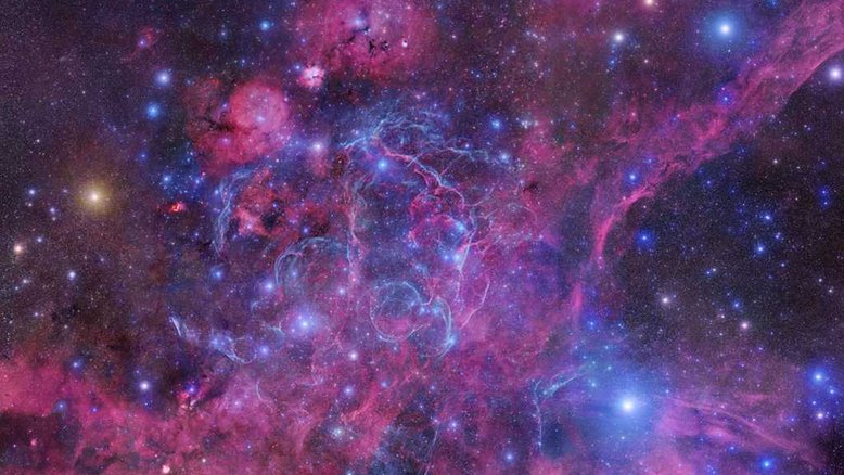 Visto na direção de estrelas coloridas perto da borda noroeste da Constelação da Vela, o mosaico acima está centrado nos filamentos brilhantes da Vela Supernova Remnant. Trata-se da nuvem de detritos em expansão por conta da explosão provocada pela morte de uma estrela massiva. A luz dessa explosão atingiu a Terra cerca de 11 mil anos atrás. Além dos filamentos chocados de gás brilhante, a catástrofe cósmica também deixou para trás um núcleo estelar incrivelmente denso e giratório, o Pulsar da Vela