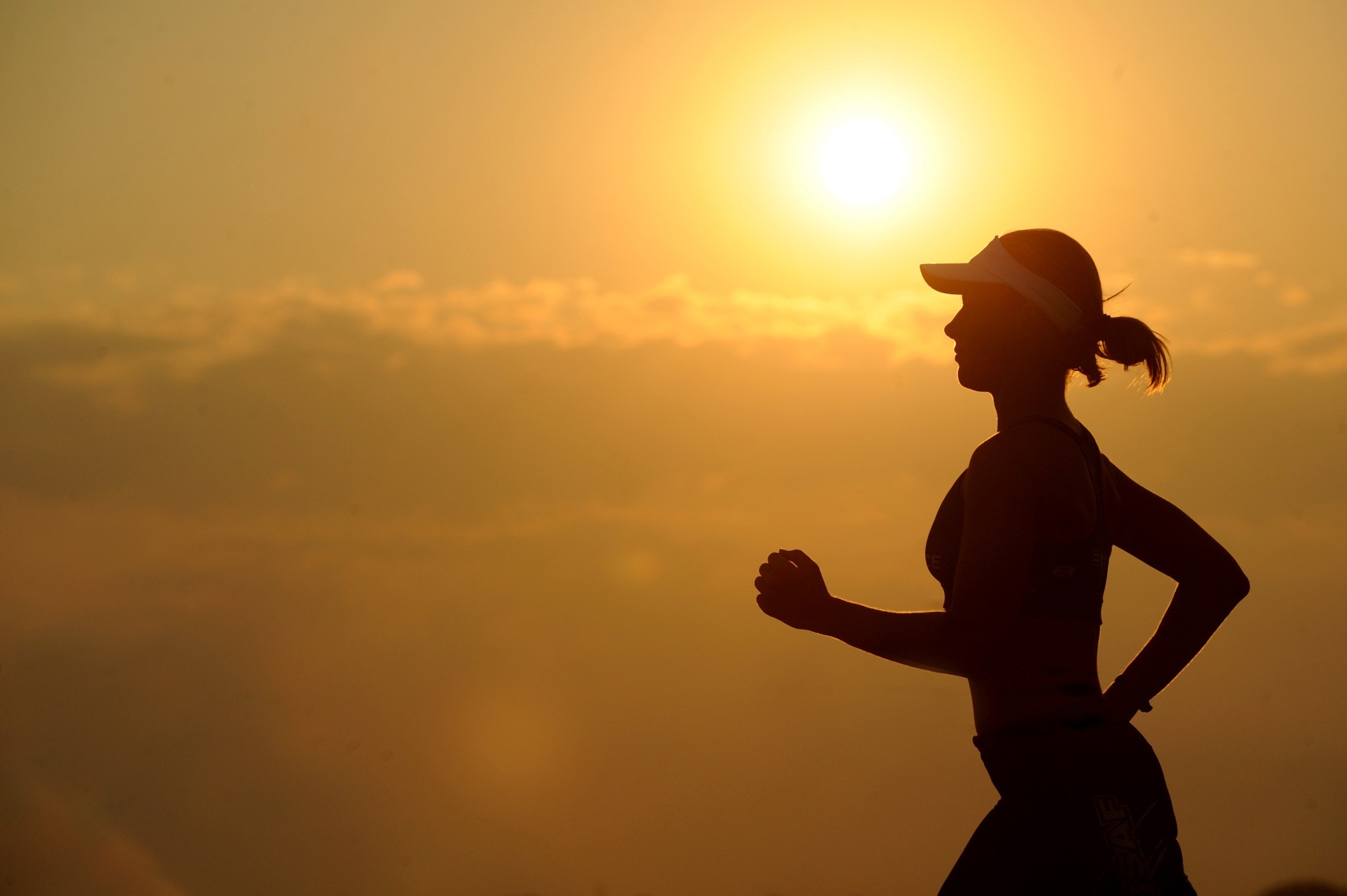 mulher correndo e sol nascendo, melhor horário para treinar