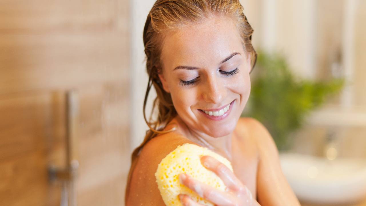mulher tomando banho e sorrindo, como prevenir acne fúngica