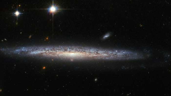 Esta imagem, capturada pela Advanced Camera for Surveys (ACS) no Telescópio Espacial Hubble da NASA/ESA, mostra a galáxia espiral NGC 5714, a cerca de 130 milhões de anos-luz de distância na constelação de Boötes (o Pastor). NGC 5714 é classificada como uma galáxia espiral Sc, mas seus braços espirais – a característica dominante das galáxias espirais – são quase impossíveis de ver, pois NGC 5714 se apresenta em um ângulo quase perfeito. Descoberta por William Herschel em 1787, a NGC 5714 foi anfitriã de um evento raro e fascinante em 2003. Uma fraca supernova apareceu cerca de 8.000 anos-luz abaixo do bojo central de NGC 5714. Supernovas são as enormes e violentas explosões de estrelas moribundas, e as uma que explodiu em NGC 5714 - não visível nesta imagem muito posterior - foi classificada como uma supernova Tipo Ib/c e denominada SN 2003dr. Foi particularmente interessante porque seu espectro mostrou fortes assinaturas de cálcio.