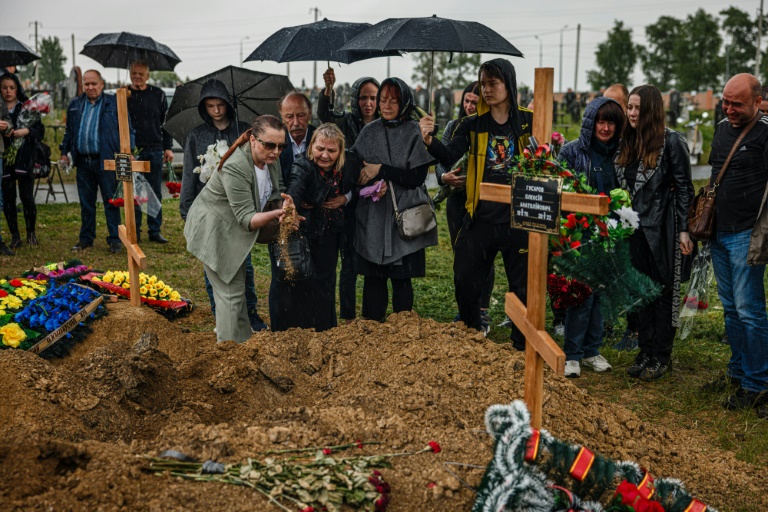 Pessoas participam do funeral de Olexandr Haponchev, de 47 anos, um soldado ucraniano morto durante a invasão russa da Ucrânia, na seção militar do cemitério 18 de Kharkiv, em Bezlioudivka, leste da Ucrânia, em 21 de maio de 2022