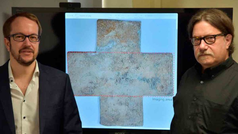 O professor da Georgia Tech David Citrin (à direita) e o professor adjunto Alexandre Locquet em frente a uma imagem da cruz funerária do século 16 usada em seu estudo. Crédito: Georgia Tech-Lorraine