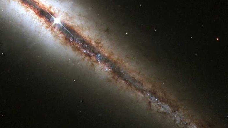 O Hubble capturou NGC 4013, essa galáxia perfeitamente 'de ponta'. A nova imagem revela com detalhes enormes nuvens de poeira e gás que se estendem ao longo e acima do disco principal da galáxia. NGC 4013 é espiral, semelhante à nossa Via Láctea, situada a cerca de 55 milhões de anos-luz da Terra, na direção da Constelação de Ursa Maior. Vista de frente, pareceria um cata-vento quase circular, mas NGC 4013 ela aparece de perfil do nosso ponto de vista. Mesmo a 55 milhões de anos-luz, a galáxia é maior que o campo de visão do Hubble, e a imagem mostra apenas um pouco mais da metade do objeto