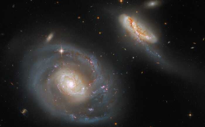 Esta imagem, feita pelo Telescópio Espacial Hubble da NASA/ESA, mostra Arp 298, um par de galáxias em interação. A maior delas é a galáxia espiral barrada NGC 7469 e IC 5283 é sua companheira diminuta. NGC 7469 também abriga um buraco negro supermassivo ativo e um anel brilhante composto por aglomerados de estrelas. Esse belo conjunto está a cerca de 200 milhões de anos-luz da Terra, na direção da Constelação do Pégaso.