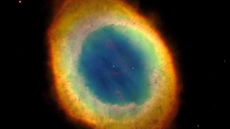 A Nebulosa do Anel (M57) é uma estrela moribunda que jogou fora parte de seu material externo, há milhares de anos. Ela está situada a 2.000 anos-luz de distância da Terra, na direção da Constelação da Lira. Nesta imagem, feita pelo Telescópio Espacial Hubble da NASA/ESA, vemos o gás lançado pela estrela central que flutua em meio a uma névoa azul, gasosa e quente. A nebulosa tem cerca de um ano-luz de diâmetro
