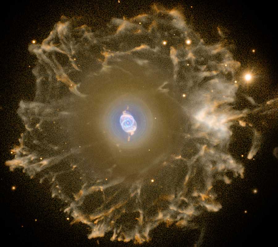Localizada a cerca de 3,3 mil anos-luz, na direção da Constelação de Draco, a Nebulosa Olho de Gato (NGC 6543) é uma das mais conhecidas nebulosas planetárias. Suas simetrias são notadas na região central desta imagem com cores falsas, que foi processada especialmente para revelar o halo de material gasoso que a circunda, com mais de três anos-luz de diâmetro. Feita com dados do Telescópio Óptico Nórdico, nas Ilhas Canárias, a imagem composta mostra a emissão estendida da nebulosa. Embora considere-se que a fase de nebulosa planetária dure cerca de 10 mil anos, estima-se que as porções filamentosas externas desse halo tenham entre 50 mil e 90 mil anos. As nebulosas planetárias representam a fase final da vida de uma estrela parecida com o Sol