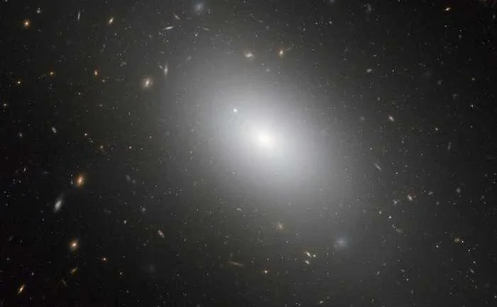 A galáxia NGC 1132 é, muito provavelmente, um fóssil cósmico ou o resultado de um enorme empilhamento de múltiplas galáxias. Colisão após colisão, construiu-se uma galáxia elíptica gigante e brilhante, mas difusa. Junto às pequenas galáxias anãs que a cercam, ela forma o "grupo fóssil" com restos de inúmeras galáxias que se fundiram. Nesta imagem, NGC 1132 está cercada por milhares de aglomerados globulares antigos, que são sobreviventes da ruptura de suas galáxias-mãe. NGC 1132 está a 300 milhões de anos-luz de distância, na Constelação de Eridanus