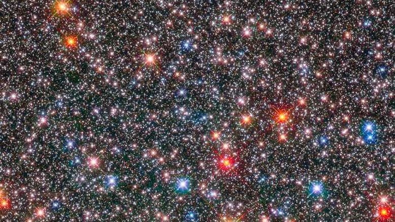 Esta imagem, feita pelo Telescópio Espacial Hubble da Nasa/ESA, mostra uma caixa de joias: são estrelas no coração da nossa Via Láctea. Estrelas gigantes vermelhas e envelhecidas coexistem com outras mais jovens e menores, brancas ou como o Sol. Essa região da Via Láctea, chamada de bulbo galáctico, é um ambiente dinâmico de estrelas de várias idades que circulam em diferentes velocidades, como se fossem viajantes. Esses movimentos dependem da composição química de cada estrela. Estrelas ricas em elementos mais pesados têm movimento menos desordenado, porém mais rápido, do que estrelas mais velhas e com deficiência desses elementos. O centro da nossa galáxia está a cerca de 26 mil anos-luz de distância, na Constelação de Sagitário
