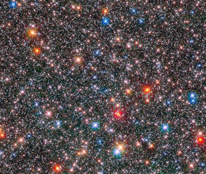 Esta imagem, feita pelo Telescópio Espacial Hubble da Nasa/ESA, mostra uma caixa de joias: são estrelas no coração da nossa Via Láctea. Estrelas gigantes vermelhas e envelhecidas coexistem com outras mais jovens e menores, brancas ou como o Sol. Essa região da Via Láctea, chamada de bulbo galáctico, é um ambiente dinâmico de estrelas de várias idades que circulam em diferentes velocidades, como se fossem viajantes. Esses movimentos dependem da composição química de cada estrela. Estrelas ricas em elementos mais pesados têm movimento menos desordenado, porém mais rápido, do que estrelas mais velhas e com deficiência desses elementos. O centro da nossa galáxia está a cerca de 26 mil anos-luz de distância, na Constelação de Sagitário