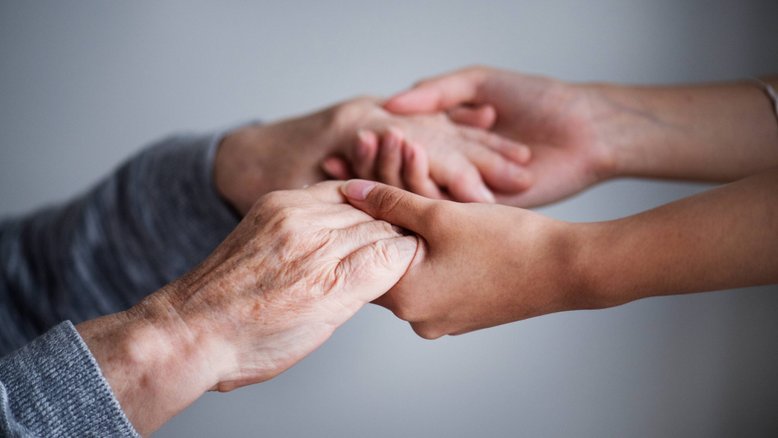 mãos de pessoa idosa segurando mãos de pessoa jovem, parkinson