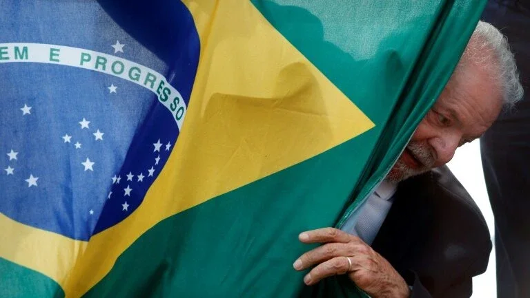 O ex-presidente Luiz Inácio Lula da Silva, favorito nas pesquisas de intenções de voto para o segundo turno, em 30 de outubro, com a bandeira do Brasil, durante ato em São Mateus, estado de São Paulo, em 17 de outubro de 2022 - AFP