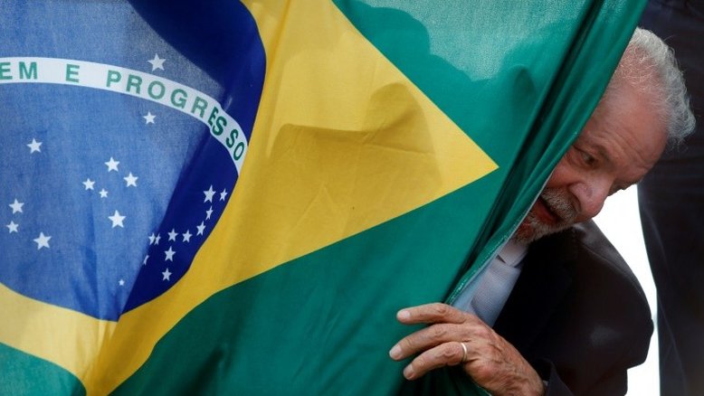 O ex-presidente Luiz Inácio Lula da Silva, favorito nas pesquisas de intenções de voto para o segundo turno, em 30 de outubro, com a bandeira do Brasil, durante ato em São Mateus, estado de São Paulo, em 17 de outubro de 2022 - AFP