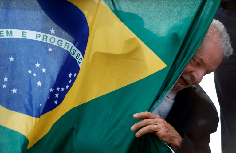 O ex-presidente Luiz Inácio Lula da Silva, favorito nas pesquisas de intenções de voto para o segundo turno, em 30 de outubro, com a bandeira do Brasil, durante ato em São Mateus, estado de São Paulo, em 17 de outubro de 2022 - AFP