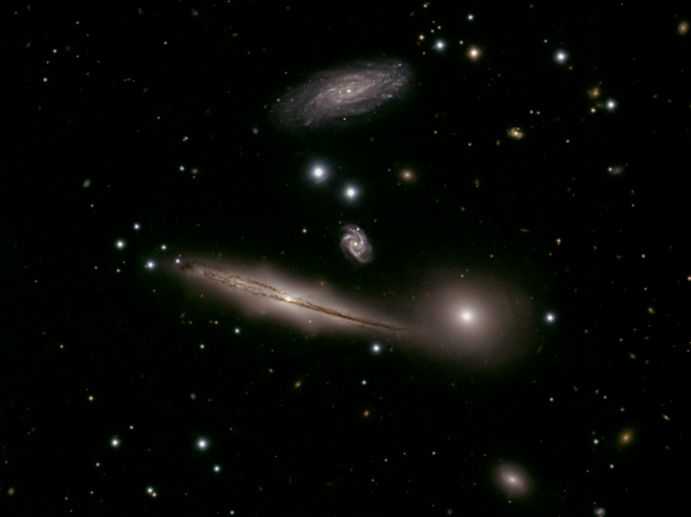 Nesta imagem, estão as galáxias de HCG (Hickson Compact Group) 87, localizadas a cerca de 400 milhões de anos-luz, na direção da Constelação de Capricórnio. A grande espiral próxima ao centro da imagem, a galáxia elíptica nebulosa imediatamente à sua direita e a espiral próxima ao topo da imagem são membros identificados, enquanto a pequena galáxia espiral no meio é provavelmente uma galáxia de fundo mais distante. A imagem também revela outras galáxias que certamente estão muito além de HCG 87. Embora não estejam exatamente em um abraço, as galáxias HCG 87 estão interagindo gravitacionalmente, influenciando a estrutura e evolução de seus companheiros de grupo