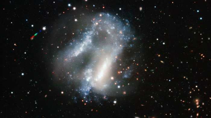 ARP 261 fica a cerca de 70 milhões de anos-luz de distância, na Constelação de Libra. Sua estrutura caótica e muito incomum se dá pela interação de duas galáxias que estão envolvidas em um movimento lento e altamente perturbador. Embora seja muito improvável que estrelas colidam, as enormes nuvens de gás e poeira certamente se chocam em alta velocidade, levando à formação de novos aglomerados brilhantes, com estrelas muito quentes, claramente vistos nesta imagem. Os caminhos das estrelas também são interrompidos, criando redemoinhos que se estendem para o canto superior esquerdo e inferior direito da imagem. Ambas as galáxias em interação provavelmente eram anãs não muito diferentes de galáxias como a Pequena e a Grande Nuvens de Magalhães, que orbitam nossa Via Láctea