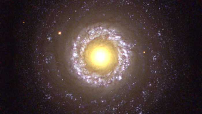 O que pode parecer um centro ensolarado é, na verdade, uma fotografia frontal da pequena galáxia espiral NGC 7742. Ela não é uma espiral comum, pois é conhecida por ser uma galáxia ativa do tipo Seyfert 2, alimentada por um buraco negro residente, visto aqui no núcleo de cor amarelada. O anel irregular e grosso em torno deste núcleo é uma área de nascimento estelar ativo. O anel está a cerca de 3 mil anos-luz do núcleo. Braços espirais bem enrolados também são visíveis. Ao redor do anel interno há uma faixa fina de material, provavelmente feito de restos de uma área de formação estelar outrora muito ativa. NGC 7742 fica a uma distância de aproximadamente 70 milhões de anos-luz, na Constelação do Pégaso