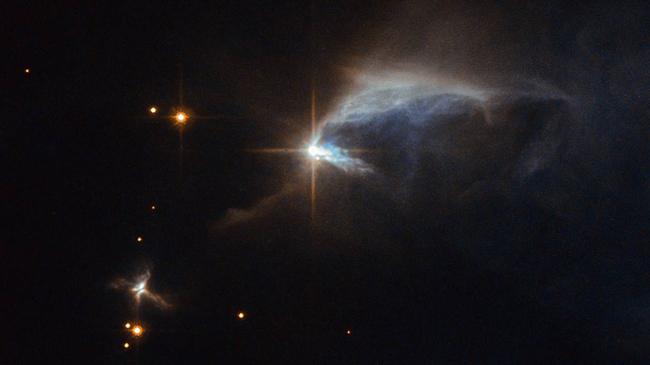 Envolto em uma espécie de envelope de poeira, o objeto desta imagem do Telescópio Espacial Hubble é a jovem estrela HBC 1. A maior parte da vida de uma estrela semelhante ao Sol dá-se em um estágio de maturidade conhecido como sequência principal. A estrela presente nesta imagem está em uma fase ainda imatura, que recebe o nome de pré-sequência principal. HBC 1 ilumina a nebulosa de reflexão IRAS 00044+6521. Formadas a partir de nuvens de poeira interestelar, as nebulosas de reflexão não emitem nenhuma luz visível própria e, em vez disso, brilham por conta de suas estrelas. HBC 1 e IRAS 00044+6521 estão a cerca de 2,7 mil anos-luz de distância, na Constelação de Cassiopéia