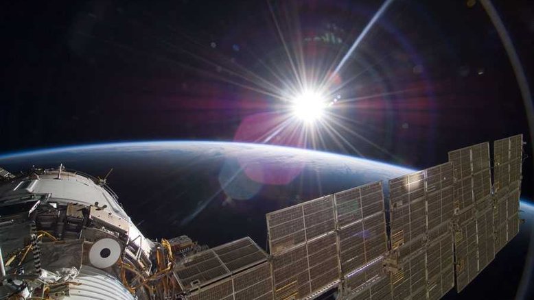 Eis uma imagem de tirar o fôlego, feita diretamente da Estação Espacial Internacional (ISS), em novembro de 2009. O Sol, a superfície terrestre e o longo braço de um painel solar estão visíveis neste registro feito quando o ônibus espacial Atlantis visitou o empreendimento científico e tecnológico que está em órbita da Terra. Os reflexos da janela e da lente hexagonal da câmera estão sobrepostos. O ônibus espacial Atlantis foi uma das missões bem-sucedidas com o objetivo de expandir e reabastecer a ISS. Resultado de uma iniciativa colaborativa entre diversos países, a ISS tem realizado inúmeros estudos científicos no ambiente de microgravidade no qual opera, além de servir como observatório terrestre
