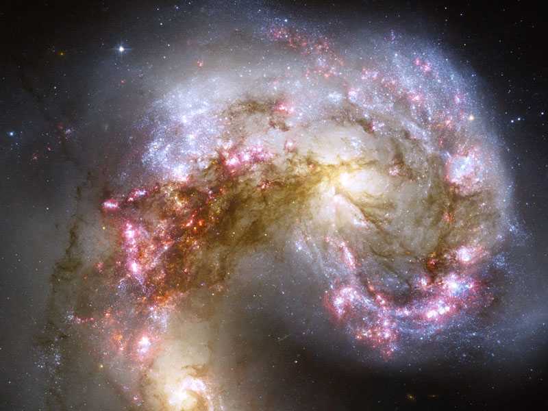 As galáxias catalogadas como NGC 4038 e NGC 4039 parecem se enfrentar, na Constelação do Corvo, a cerca de 65 milhões de anos-luz de distância. No entanto, quando duas galáxias colidem, as suas estrelas geralmente não fazem o mesmo. Isso ocorre porque as galáxias são preenchidas principalmente por espaços vazios, de forma que as estrelas ocupam apenas uma pequena parcela do seu espaço. Durante o processo de colisão, que pode durar centenas de milhões de anos, no entanto, uma galáxia pode alterar a outra gravitacionalmente. No encontro acima, os pilares de poeira escura marcam nuvens moleculares massivas que estão sendo comprimidas, gerando o rápido nascimento de milhões de estrelas
