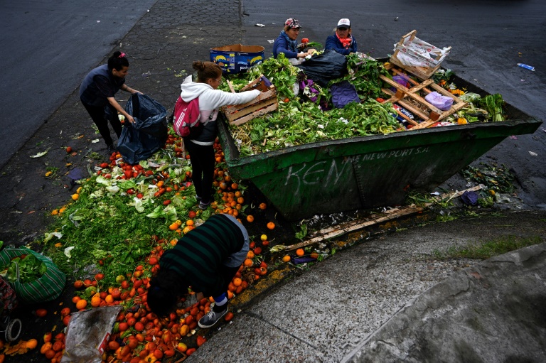 Pessoas procuram verduras em boas condições entre os alimentos descartados no Mercado Central de Buenos Aires, em 9 de junho de 2023 - AFP