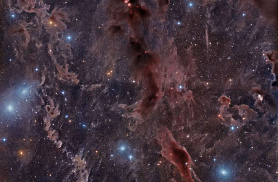 Estes filamentos estão localizados na direção da Constelação de Touro, entre o aglomerado de estrelas das Plêiades (Messier 45) e a Nebulosa da Califórnia (NGC 1499). Várias estrelas brilhantes são visíveis, com sua luz azul refletida na poeira marrom. Outras estrelas parecem excepcionalmente vermelhas, pois o vermelho é a cor que permanece depois que o azul é espalhado. Embora pareça serena, a cena é, na verdade, um ciclo contínuo de renascimento. Nós maciços de gás e poeira entram em colapso gravitacional, formando novas estrelas que, depois, criam mais poeira com sua luz e ventos energéticos
