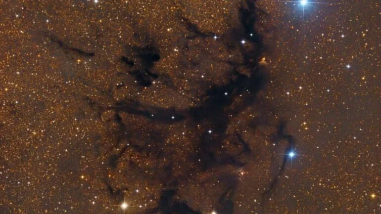 Parte de uma extensão escura que divide o plano de nossa galáxia, a Via Láctea, a Fenda de Aquila (ou Fenda da Águia) atravessa os céus do planeta Terra perto da brilhante estrela Altair, a principal da Constelação da Águia. Suas nuvens moleculares empoeiradas provavelmente contêm matéria-prima para formar centenas de milhares de estrelas. Este close telescópico revela a região em um complexo fragmentado de nuvens escuras, identificado como LDN 673. Estima-se que essas nuvens escuras estejam a cerca de 600 anos-luz de distância da Terra