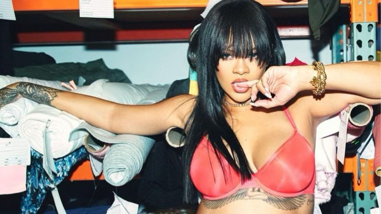 rihanna usando sutiã rosa na frente de um estoque de roupas