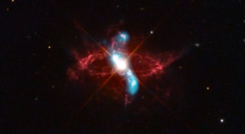 A estrela variável R Aquarii é, na verdade, um sistema estelar binário em interação, com duas estrelas que parecem ter uma relação simbiótica. A cerca de 710 anos-luz de distância, na Constelação de Aquário, ela consiste em uma estrela gigante vermelha fria e uma estrela anã branca quente e densa. Elas estão em órbita mútua, em torno de seu centro de massa comum. A luz visível do sistema binário é dominada pela gigante vermelha, mas o material no envelope estendido da estrela gigante fria é puxado pela gravidade para a superfície da anã branca, menor e mais densa, desencadeando uma explosão termonuclear que lança material para o espaço