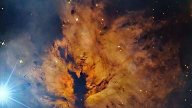 O que ilumina a Nebulosa da Chama (NGC 2024)? A 1,5 mil anos-luz de distância, na direção da Constelação de Órion, encontra-se uma nebulosa que, por conta de seu brilho e faixas de poeira escura, parece um fogo ondulante. A estrela brilhante, Alnitak, a mais oriental no Cinturão de Órion, visível na extrema esquerda, brilha com luz energética que afasta os elétrons das grandes nuvens de gás hidrogênio que residem lá. Grande parte do brilho resulta quando os elétrons e o hidrogênio ionizado se recombinam. A Nebulosa da Chama faz parte do Complexo da Nuvem Molecular de Órion, uma famosa região de formação estelar