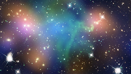 Esta imagem composta mostra a distribuição de matéria escura, galáxias e gás quente no núcleo do aglomerado de galáxias em fusão Abell 520. Formado a partir de uma colisão violenta de massivos aglomerados de galáxias, ele está localizado a cerca de 2,4 bilhões de anos-luz da Terra, na direção da Constelação de Orion. Dados de raios-X, em verde, mostram o gás quente em colisão. Os dados ópticos estão visíveis em vermelho, verde e azul. A luz estelar das galáxias dentro dos aglomerados aparece em laranja. As áreas azuis identificam a maior parte da massa no aglomerado, que é dominado por matéria escura. A matéria escura é uma substância invisível que constitui a maior parte da massa do universo