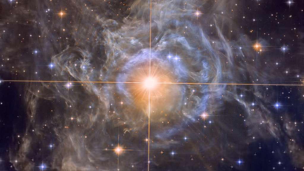 A pulsante RS Puppis, a estrela mais brilhante no centro da imagem, é cerca de dez vezes mais massiva que o nosso Sol e, em média, 15 mil vezes mais luminosa. Ela é uma estrela variável do tipo Cefeida, uma classe de estrelas cujo brilho é usado para estimar distâncias entre galáxias com o objetivo de estabelecer uma escala cósmica. À medida que o RS Puppis pulsa, as suas mudanças regulares no brilho também são vistas ao longo da nebulosa circundante como um eco de luz. Usando medições do atraso de tempo e do tamanho angular da nebulosa, a velocidade conhecida da luz permite determinar geometricamente a sua distância com relativa precisão