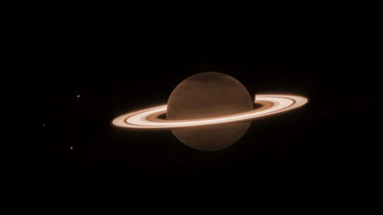 Em junho passado, o Telescópio Espacial James Webb voltou-se para o famoso mundo do gigante dos anéis no Sistema Solar, o planeta Saturno, para fazer suas primeiras observações no espectro próximo ao infravermelho. Saturno parece escuro nesse comprimento de onda, pois o gás metano absorve quase toda a luz solar que incide na atmosfera. No entanto, os anéis gelados permanecem relativamente brilhantes, revelando uma aparência incomum nestas imagens