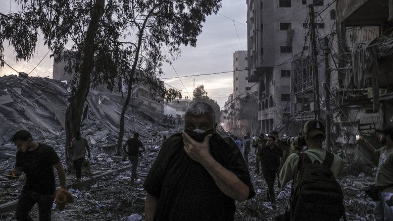 Pessoas caminham sobre os escombros de uma torre destruída em um ataque aéreo israelense na cidade de Gaza em 7 de outubro de 2023