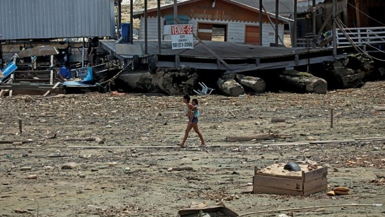 Mulher carrega criança no leito seco de um rio, devido à grave seca no rio Negro, na Marina do Davi, a oeste de Manaus, Amazonas, em 29 de setembro de 2023 - AFP