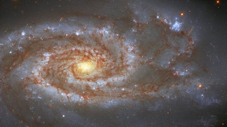 A aproximadamente 85 milhões de anos-luz da Terra, na Constelação de Libra, está NGC 5861, a galáxia registrada nesta imagem feita pelo Telescópio Espacial Hubble. NGC 5861 é uma galáxia espiral intermediária. Isso significa que ela tem uma forma que fica entre a de uma galáxia espiral barrada - dotada de uma estrutura central em forma de barra - e a de uma galáxia espiral não barrada, sem uma barra central. Duas supernovas, SN1971D e SN2017erp, foram observadas nela