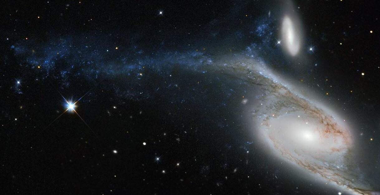 NGC 6872 é uma galáxia de formato incomum, localizada na direção da Constelação de Pavo (“O Pavão”). A sua deformação é resultado das interações com a galáxia menor, vista logo acima nesta imagem, cuja designação é IC 4970. Ambas ficam a cerca de 300 milhões de anos-luz de distância da Terra. De ponta a ponta, NGC 6872 mede mais de 500 mil anos-luz de diâmetro, tornando-a a segunda maior galáxia espiral descoberta até hoje. Para colocar isso em perspectiva, a nossa galáxia, a Via Láctea, mede entre 100 mil e 120 mil anos-luz de diâmetro, fazendo com que NGC 6872 tenha cerca de cinco vezes o seu tamanho