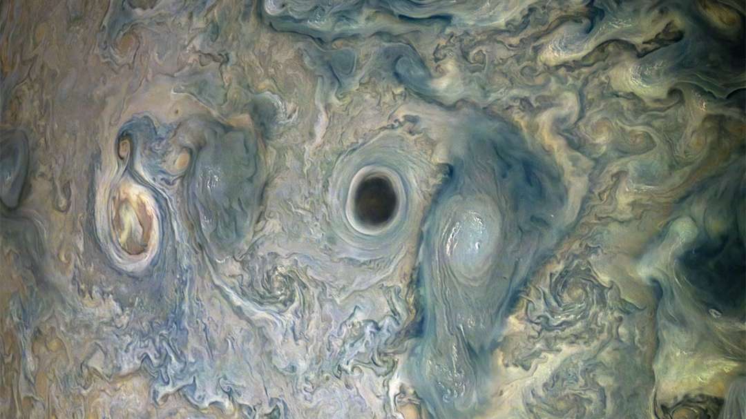 O que é a mancha escura que aparece em Júpiter? Ninguém sabe ao certo. Durante uma das passagens da sonda Juno, da NASA, em torno do gigante gasoso, as imagens revelaram uma nuvem escura, que foi informalmente apelidada de Abismo. Os padrões de nuvens circundantes mostram que o Abismo está no centro de um vórtice. Como as formações escuras na atmosfera de Júpiter tendem a ser mais profundas do que as formações luminosas, o Abismo pode realmente ser o buraco profundo que parece. Esta imagem foi capturada enquanto Juno passava a cerca de 15 mil km acima do topo das nuvens de Júpiter