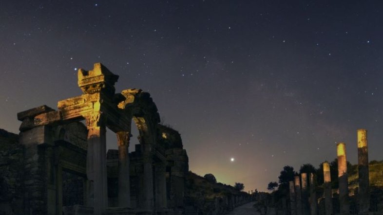 Registrada em junho de 2008, esta paisagem celeste mostra o planeta Júpiter acima do horizonte sudeste e as ruas de mármore da antiga cidade portuária de Éfeso, localizada na atual Turquia. À esquerda está um templo dedicado ao imperador romano Adriano, que reinou de 117 a 138 d.C. O lindo céu noturno também inclui o arco da Via Láctea. As luzes no horizonte vêm da cidade vizinha de Selçuk