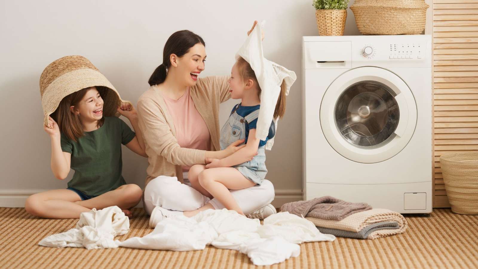 Mãe e filhas brincam durante o processo de lavar roupas