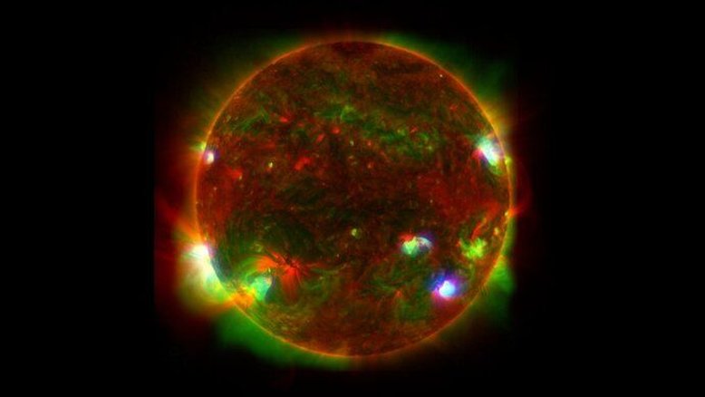 Os comprimentos de onda da luz de três observatórios espaciais estão sobrepostos nesta imagem do Sol. Mesmo num dia ensolarado, os olhos humanos não conseguem ver toda a luz que a nossa estrela mais próxima emite. Raios X de alta energia, emitidos pelo material mais quente na atmosfera solar, precisam da tecnologia presente no Nuclear Spectroscopic Telescope Array (NuSTAR) para serem revelados. Embora o observatório normalmente estude objetos fora do Sistema Solar – como buracos negros massivos e estrelas em colapso – ele também forneceu informações sobre o Sol. Os dados do NuSTAR (em azul) estão sobrepostos aos da Missão Hinode, da Agência Japonesa de Exploração Aeroespacial (em verde) e também aos do Solar Dynamics Observatory (em vermelho)