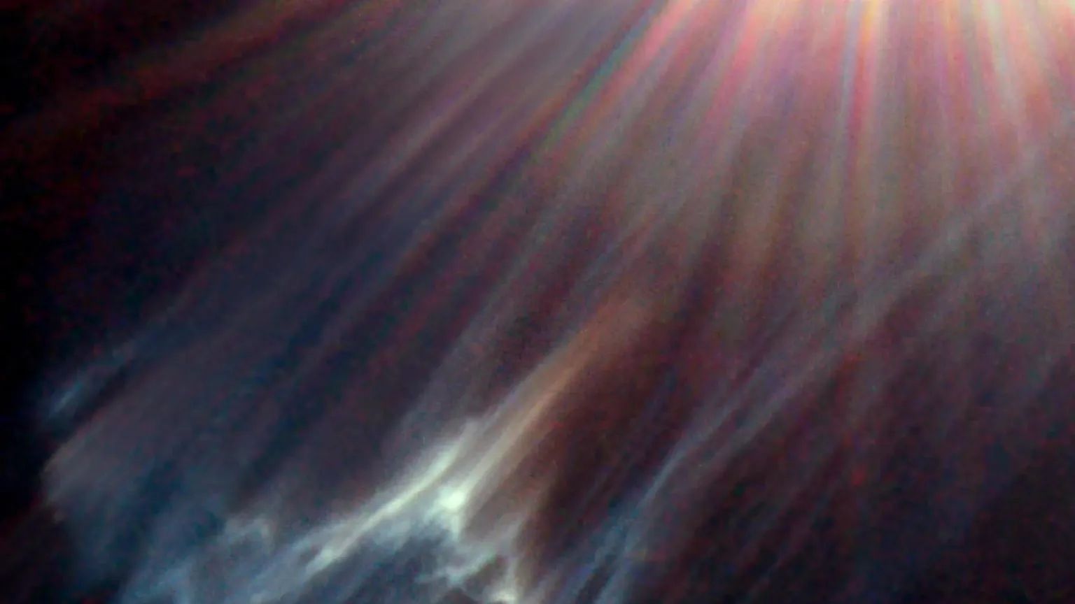 Nesta imagem, vê-se uma nuvem interestelar sendo destruída por uma das estrelas mais brilhantes do Aglomerado das Plêiades (Messier 45 ou M45), localizado a cerca de 445 anos-luz de distância, na Constelação de Touro. A luz da estrela é refletida na superfície de nuvens negras de gás frio misturadas com poeira. Isso produz uma nebulosa de reflexão. Comumente chamado de Sete Irmãs, M45 é conhecido como um aglomerado estelar aberto. Contém mais de mil estrelas que estão ligadas pela gravidade, mas é visualmente dominada apenas por algumas das mais brilhantes. Uma dessas estrelas, Merope, está localizada fora do quadro desta imagem, no canto superior direito. Os raios de luz coloridos que emanam da estrela são um fenômeno óptico produzido dentro do telescópio