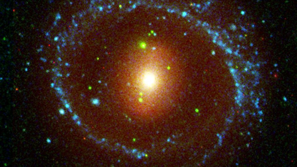 Esta imagem mostra a galáxia NGC 1291, localizada a cerca de 33 milhões de anos-luz de distância, na direção da Constelação de Eridanus. NGC 1291 é notável por sua barra interna incomum e estrutura de anel externo. O azul representa a luz ultravioleta, capturada pelo detector de comprimento de onda longo do telescópio da missão Galaxy Evolution Explorer, da Nasa. O verde mostra a luz ultravioleta do detector de comprimento de onda curto e o vermelho mostra a luz visível vermelha fornecida pelo Observatório Interamericano de Cerro Tololo, Chile
